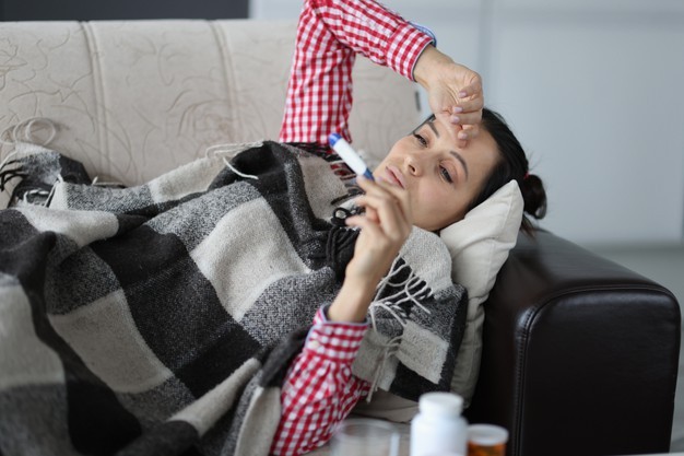 Woman With Cold Lying Sofa Covers Looking Thermometer Isolation Respiratory 151013 20139